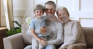 Smiling excited three male generations family resting on couch.