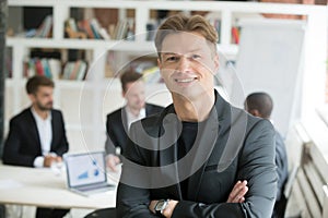 Smiling executive in suit standing arms crossed looking at camer