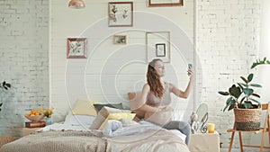 Smiling expectant mother making selfie photo. Pregnant woman relaxing home.