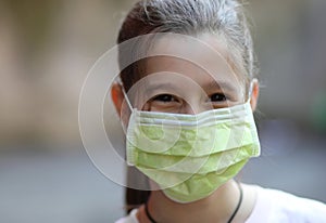 Smiling eyes of a pretty little girl with surgical mask during t