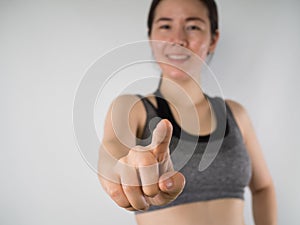 Young Asian woman in sport bra pointing finger on isolated .