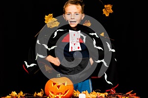 Smiling face young boy costume dressed as halloween cosplay of scary dacula near a jack`o pumpkin