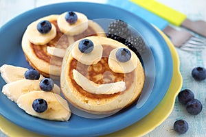 Smiling faces on pancakes with fresh fruit for kids