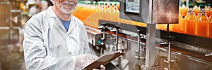 Smiling factory engineer maintaining record on clipboard in factory