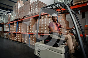 Smiling factory worker driving around warehouse stocking up parcels for delivery.