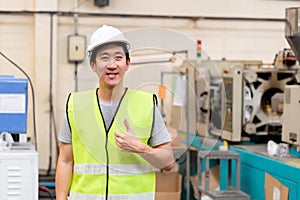 Smiling factory worker with safety hard in industrial facilities with thumbs up