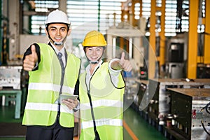 Smiling factory workers thumb up