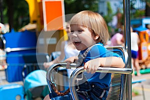 Smiling fair child boy riding amusement ride