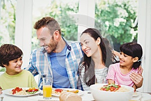 Smiling family with arm around while sitting at dining table