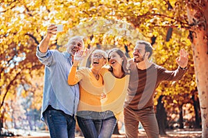 Smiling family on an autumns day in park make selfie