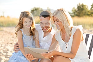 Smiling family at beach with tablet pc computer