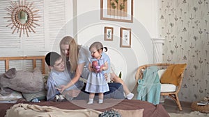 Smiling family in bed, where dad gives a little daughter a toy, and mom picks up the phone.