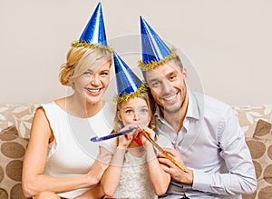 Smiling family in blue hats blowing favor horns