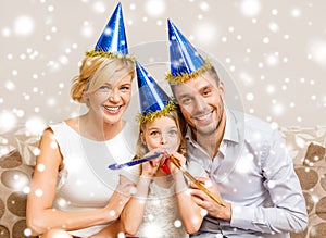 Smiling family in blue hats blowing favor horns