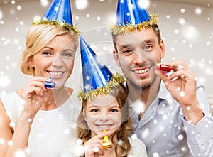 Smiling family in blue hats blowing favor horns