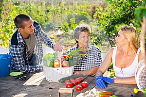 Smiling family breezily chatting at wooden table in garden