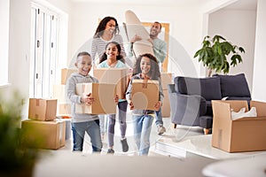 Smiling Family Carrying Boxes Into New Home On Moving Day