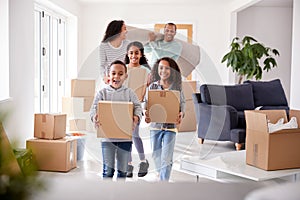 Smiling Family Carrying Boxes Into New Home On Moving Day