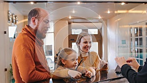 A smiling family checking in the hotel - standing by the reception