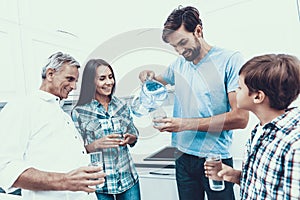 Smiling Family Drinking Water in Glasses at Home.