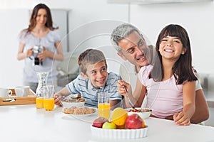 Smiling family eating breakfast in kitchen together