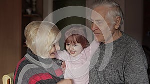 Smiling family grandfather, grandmother with child granddaughter at home