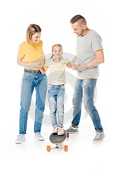 smiling family holding hands of little daughter on skateboard