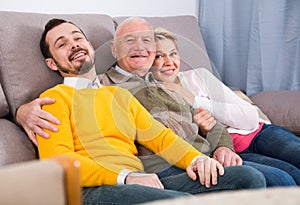 Smiling family hugging sitting on sofa