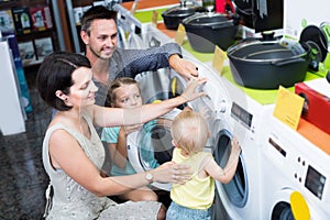 Smiling family with kids shopping washer in household