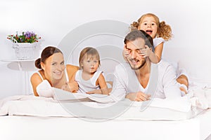 Smiling family laying on white bed in pajamas