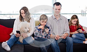 Smiling family members spending time playing with smartphones