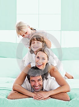 Smiling family piled on top of dad