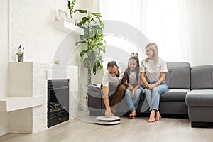 Smiling family pointing at robotic vacuum cleaner