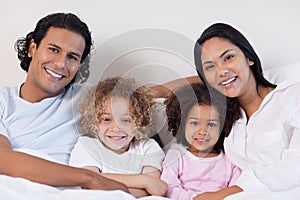 Smiling family sitting on the bed together