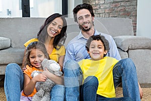 Smiling family sitting on carpet in living room