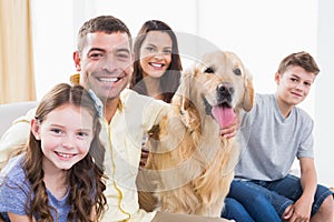 Smiling family sitting with Golden Retriever on sofa