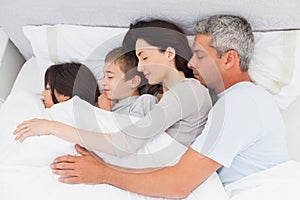 Smiling family sleeping together in bed