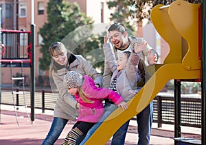 Smiling family spending time at children slide