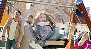 Smiling family spending time at children swings