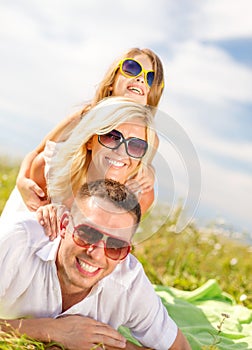 Smiling family in sunglasses lying on blanket