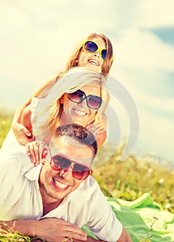 Smiling family in sunglasses lying on blanket