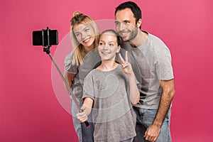 smiling family taking selfie on smartphone while daughter showing peace symbol, isolated