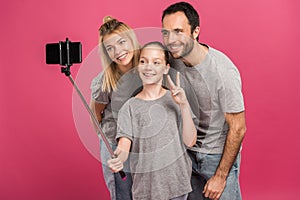 smiling family taking selfie on smartphone while daughter showing peace symbol, isolated photo