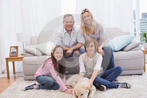 Smiling family with their pet yellow labrador on the rug