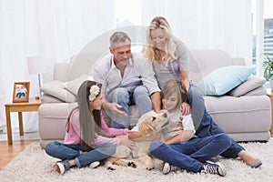 Smiling family with their pet yellow labrador on the rug