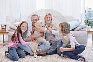 Smiling family with their pet yellow labrador on the rug