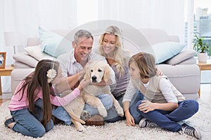 Smiling family with their pet yellow labrador on the rug