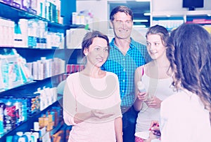 Smiling family of three consulting druggist