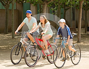 Smiling family of three cycling on street road