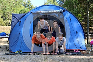 Smiling family with three happy children and tent in camping